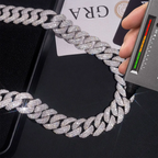 Iced out Cuban link chain necklace being tested with diamond tester on black surface