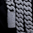 Close-up of a thick iced out Cuban link chain with sparkling stones on a black fabric background.