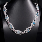 Silver chain necklace with blue and pink gemstone floral accents on black display