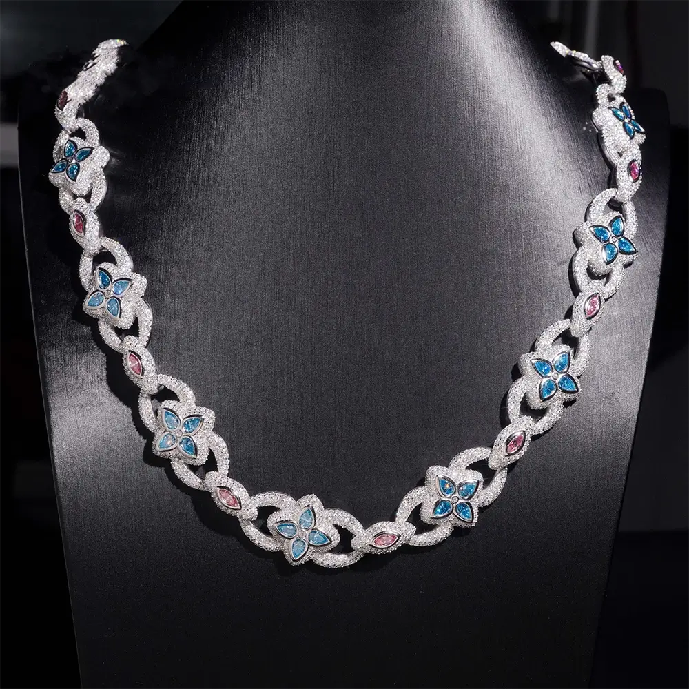 Silver chain necklace with blue and pink gemstone floral accents on black display
